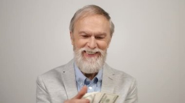 Mutlu yaşlı adam içeride para sayıyor. Modern stüdyoda dolarları elinde tutan zengin adam..