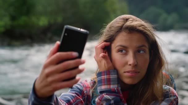 徒步旅行者在智能手机视频聊天前整理头发。女孩在镜头前挥手 — 图库视频影像