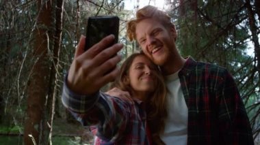 Cep telefonundan selfie çeken bir çift. Kadın ve erkek telefon kamerasına gülümsüyor.