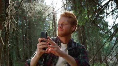 Ormanda akıllı telefondan fotoğraf çeken bir adam. Ormanda cep telefonu kullanan adam..