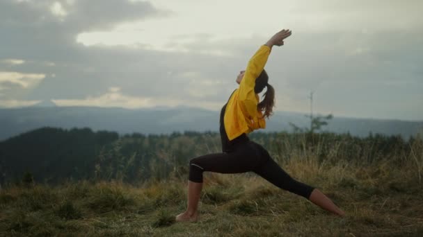 Mulher de ioga em pé em pose de guerreiro. Fit menina meditando nas montanhas — Vídeo de Stock