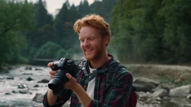 Fotograf schaut Bilder in die Kamera. Lächelnder Kerl posiert vor der Kamera — Stockvideo