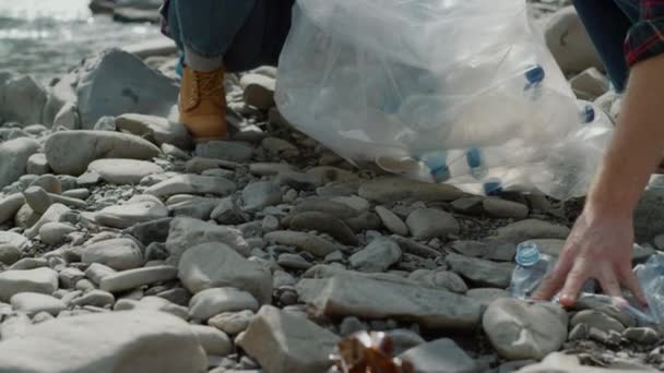 Vrijwilligers verzamelen flessen in zak.Vrouw en man schoonmaken van rivier uit afval — Stockvideo