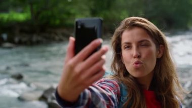 Cep telefonundan selfie çeken bir kız. Neşeli kadın kameraya surat asıyor.