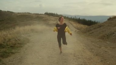 Dağlarda koşan bir kadın. Antrenmandan sonra iyi sonuçlar alan mutlu bir sporcu.