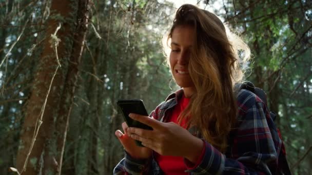 Meisje met smartphone in het bos. Wandelaar op zoek naar mobiel netwerk in het bos — Stockvideo