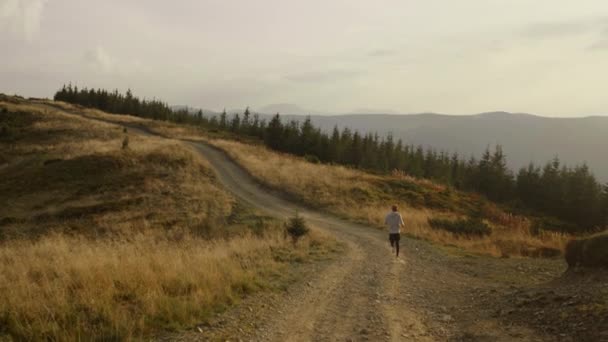 Athlète actif faisant du jogging en montagne. Jeune homme courant sur la route — Video