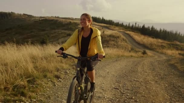 Cykla på motionscykel i fjällen. Leende kvinna ridning mountainbike — Stockvideo