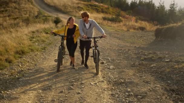 Meisje en jongen met fietsen gaan op de weg Fietsers nemen rust na het sporten — Stockvideo