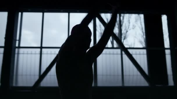 Esnek dansçı silueti karanlık spor salonunda ellerini hareket ettiriyor. Sıska kadın içeride dans ediyor.. — Stok video