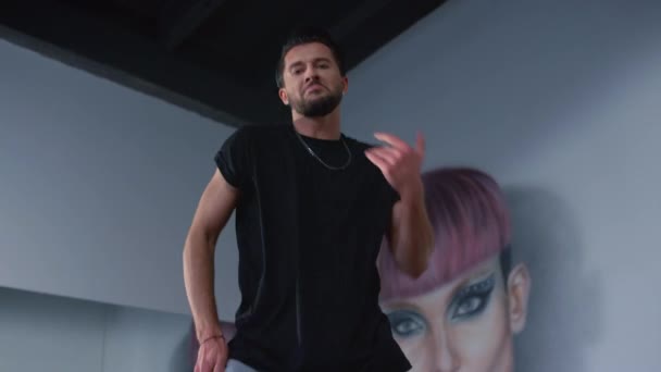 Bailarina de estilo urbano mirando cámara en clase de baile. Hombre sonriente bailando adentro. — Vídeos de Stock