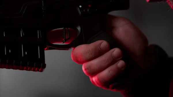 Muž držící v ruce pušku. Mužský zabiják mačká spoušť pistole — Stock fotografie