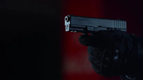 Male sniper in gloves holding gun. Closeup soldier aiming pistol at mission — Stock Photo, Image