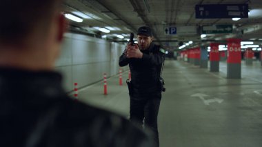 Polis, suçluyu operasyonda tutukladı. Erkek polis, şüpheliyi silahla hedef alıyor.