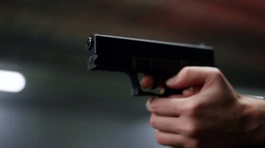 Erkek eli dolu silah tutuyor. Polis silahla ateş ediyor.