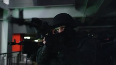 Maskeli terorist ekibi keskin nişancı tüfekleriyle çelik köprüde yürüyor.