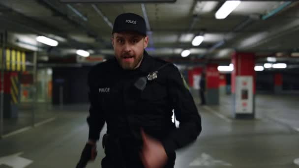 Odważny policjant biegający na parkingu. mężczyzna policjant celowanie pistolet — Wideo stockowe