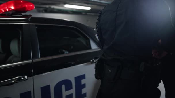 Un policier guide un homme dans une voiture de police. Un policier arrête un suspect — Video