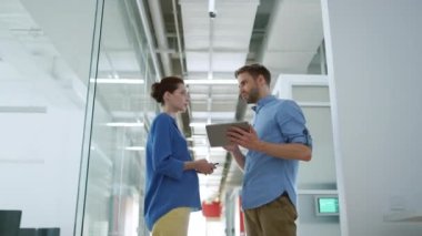 Modern ofiste meslektaşlar tablet gibi görünüyor. İnsanlar içeride iş konuşuyorlar..