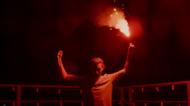 Agresivní muž hořící signální erupci na střeše. Fotbalový ventilátor stojící s ohněm — Stock video