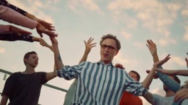 Diskoda zıplayan yakın plan hipster adam. İnsanlar çatıda eğleniyor.. 