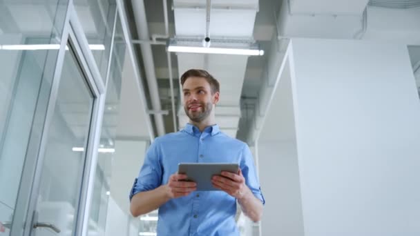 Uomo d'affari che va con tablet lungo ufficio moderno. Uomo mano agitando al chiuso. — Video Stock