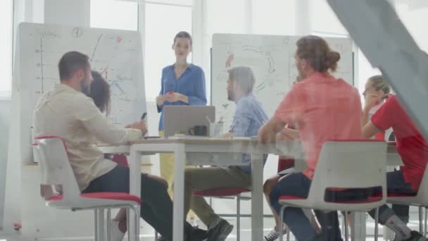 Durch Glas lauschen die Menschen dem Büro des Chefs. Trainerin stellt Projekt vor — Stockvideo