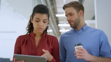 Ofiste tablet kullanan çok ırklı insanlar. Yürürken konuşan meslektaşlar.