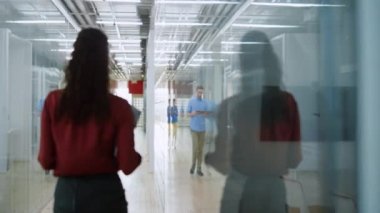 Modern ofiste tabletle koşuşturan bir adam. İnsanlar koridorda yürüyorlar..