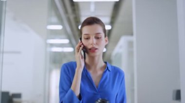 İçeride cep telefonuyla konuşan bir kadın. Kâğıt bardakla çalışan bir iş kadını.