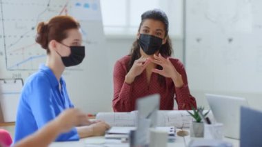 Ofiste beyin fırtınası yapan maskeli insanlar. Korumalı takım masa başında oturuyor.. 