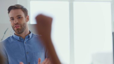 Erkek konuşmacı sunum ofisinde mutlu. İnsanlar iş adamını alkışlıyor.