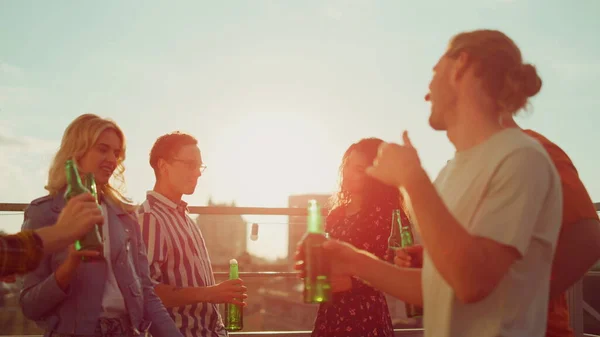 Multietniske venner slapper av med øl på terrassen. Vakre mennesker henger sammen – stockfoto