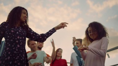 Neşeli arkadaşlar çatı partisinde eğleniyor. Diskoda dans eden Afrikalı kızlar.