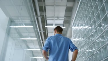 Bilinmeyen işadamı modern uzayda tabletle dolaşıyor. Etrafa bakan adam.