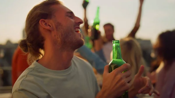 ชายที่มีความสุข ดื่มเบียร์ที่ปาร์ตี้บนดาดฟ้า ชายที่มีความสุขเต้นรํากลางแจ้ง . — ภาพถ่ายสต็อก