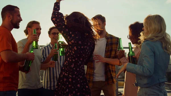 Többnemzetiségű barátok koccintanak sörrel a naplemente partin. Mosolygó barátok táncolnak. — Stock Fotó