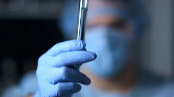 Vídeo macro del médico sosteniendo el tubo de prueba en las manos con guantes azules. Máscara protectora. —  Fotos de Stock