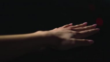 Güzel bir kadın eli parlak yüzeyde uzanıyor. Makro manikürlü pembe tırnaklar.