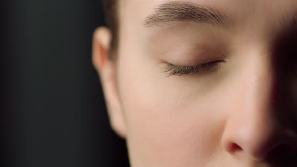 Extreme close up of half face shot of serious female face indoors. Closing eyes. — Stock Video