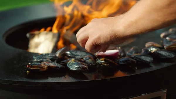 Unbekannter grillt draußen Muscheln. Männlicher Koch bereitet Meeresfrüchte auf Mangal zu — Stockfoto