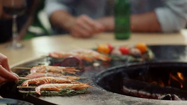 不认识的人把虾放在外面的烤架上烤.在网格上烹饪海鲜的女人 — 图库照片