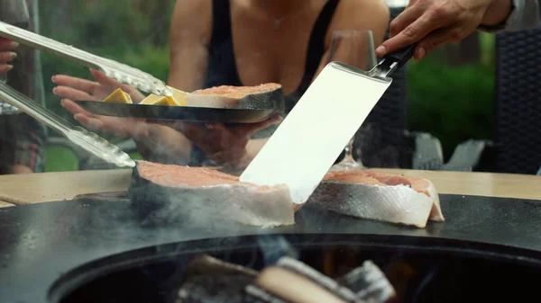 Grabbar som använder köksredskap utanför. Okända män matlagning fisk på mangal utomhus — Stockfoto