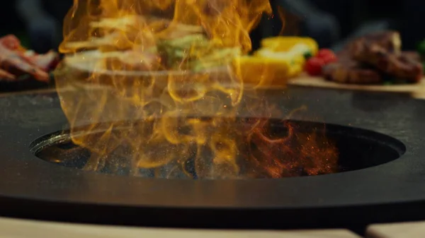 Helle Flammen lodern im Grill. Unbekannter gießt Öl in Flammen — Stockfoto