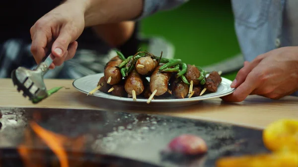 Um tipo desconhecido a pôr vegetais no prato lá fora. Homem chef usando fórceps ao ar livre — Fotografia de Stock