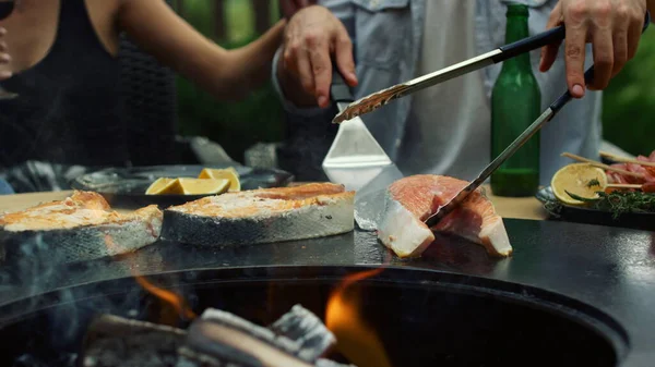 Ein unkenntlicher Mann kontrolliert draußen die Fischzubereitung. Kerl mit Küchenwerkzeug — Stockfoto