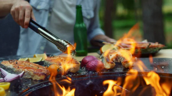 Nerozpoznatelný muž venku vaří ryby na grilu. Kuchař dokončuje proces vaření — Stock fotografie