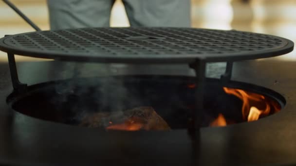 Unrecognized man putting firewood in grate outdoors. Guy using poker outside — Stock Video