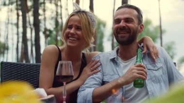 Izgara partisinde gülen neşeli bir çift. Gülümseyen kız dışarıda sarılan adam..