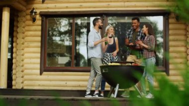 Çok ırklı arkadaşlar dışarıda parti yapıyorlar. İnsanlar evin yakınında sohbet ediyorlar.